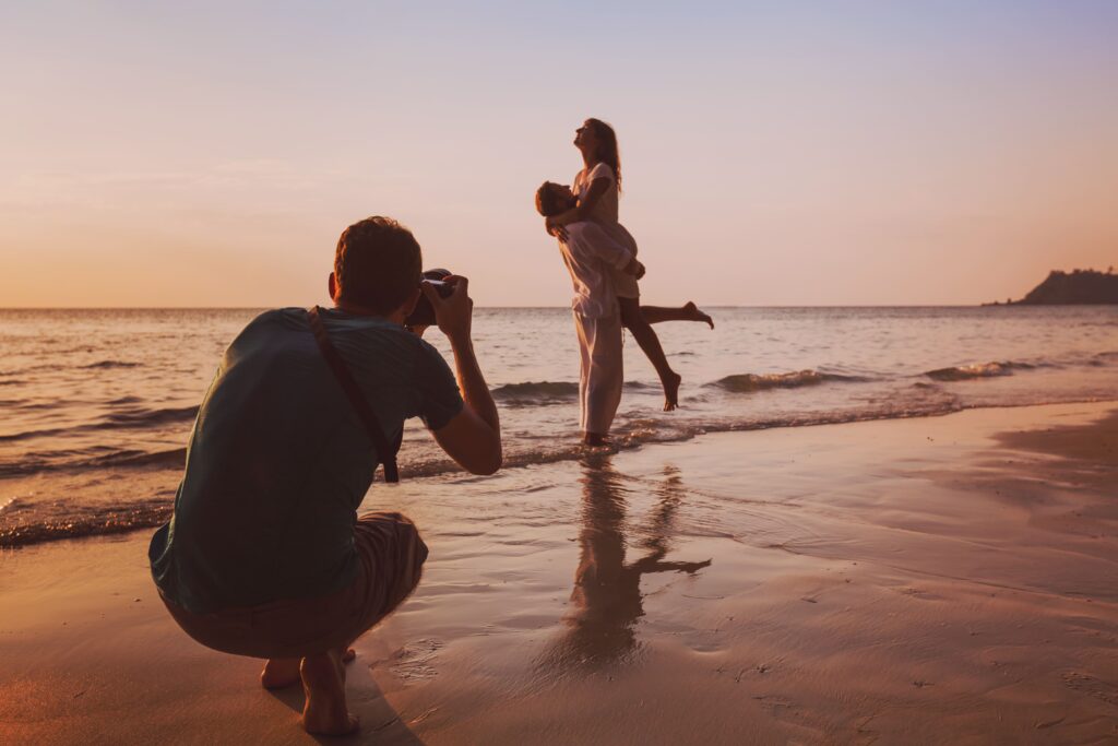 A photographer shooting a couple on the beach at sunset